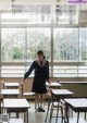 A woman in a school uniform standing in front of a window.